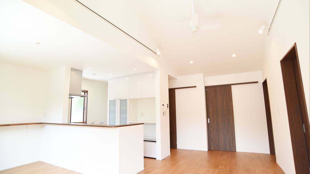 キッチンを囲むカウンターと、濃い木目の建具が白い壁を引き締めます