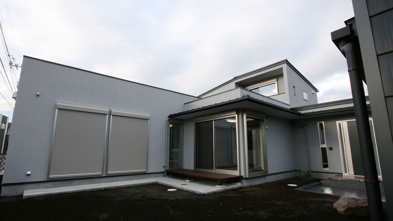 グレーの外壁に大きな窓とデッキ、庭側から見た建物