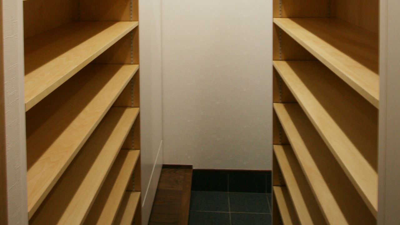 玄関脇の収納は、両側に木の棚板を並べた造作の下駄箱