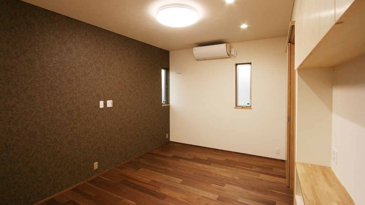 濃い色のアクセント壁と縦長の窓で、落ち着きのある居室に
