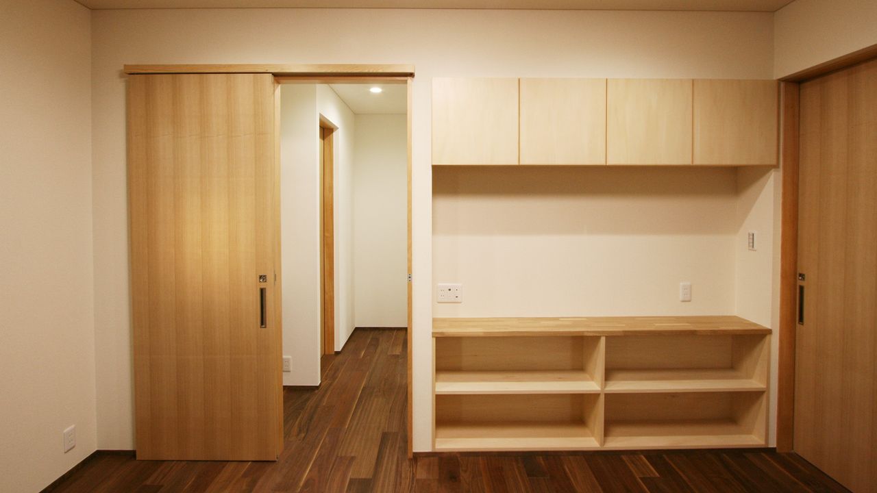 木の引き戸と吊り戸棚、オープン棚を一面にそろえた造作収納