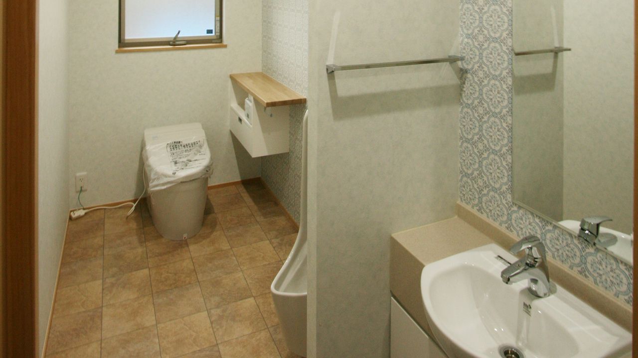 タイル調の床に、柄のある壁紙を合わせたトイレと手洗い