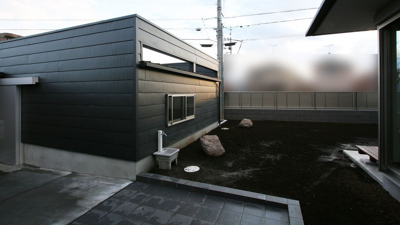 屋根材を張ったガレージの外壁、庭側には立水栓を設置