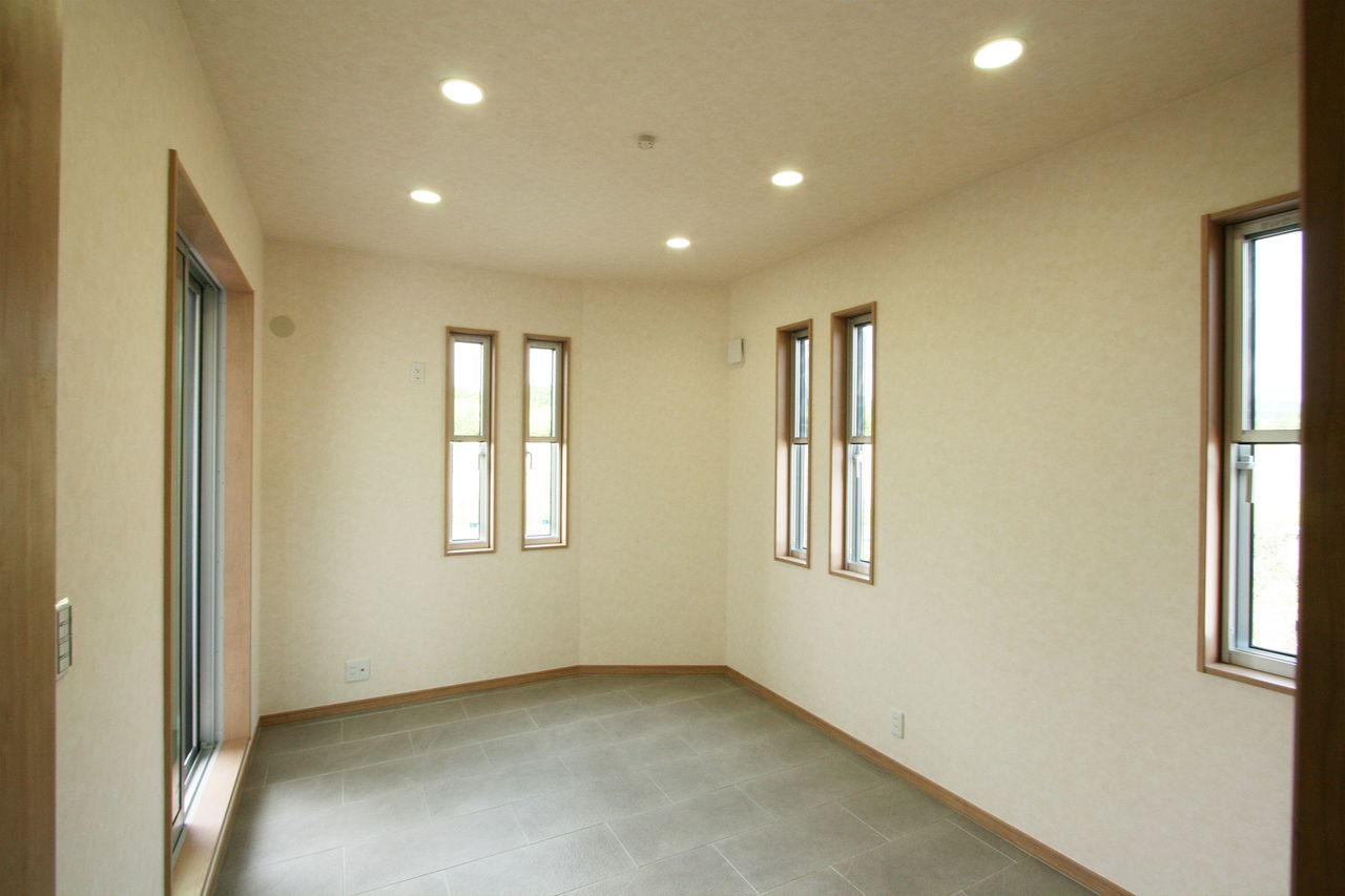 縦長の窓を並べたタイル張りの部屋、壁がゆるく折れています