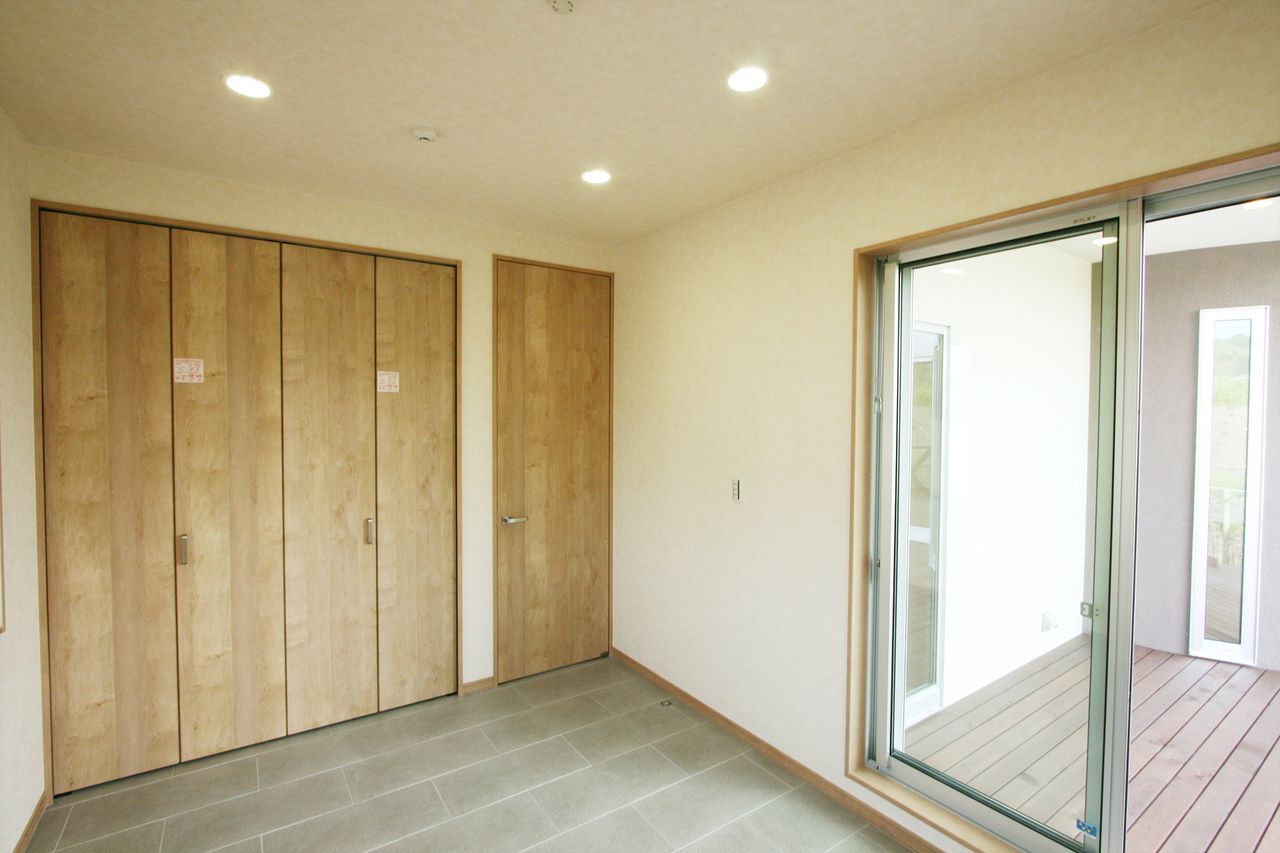 木目の折れ戸収納を壁一面に、窓の外には中庭のデッキ