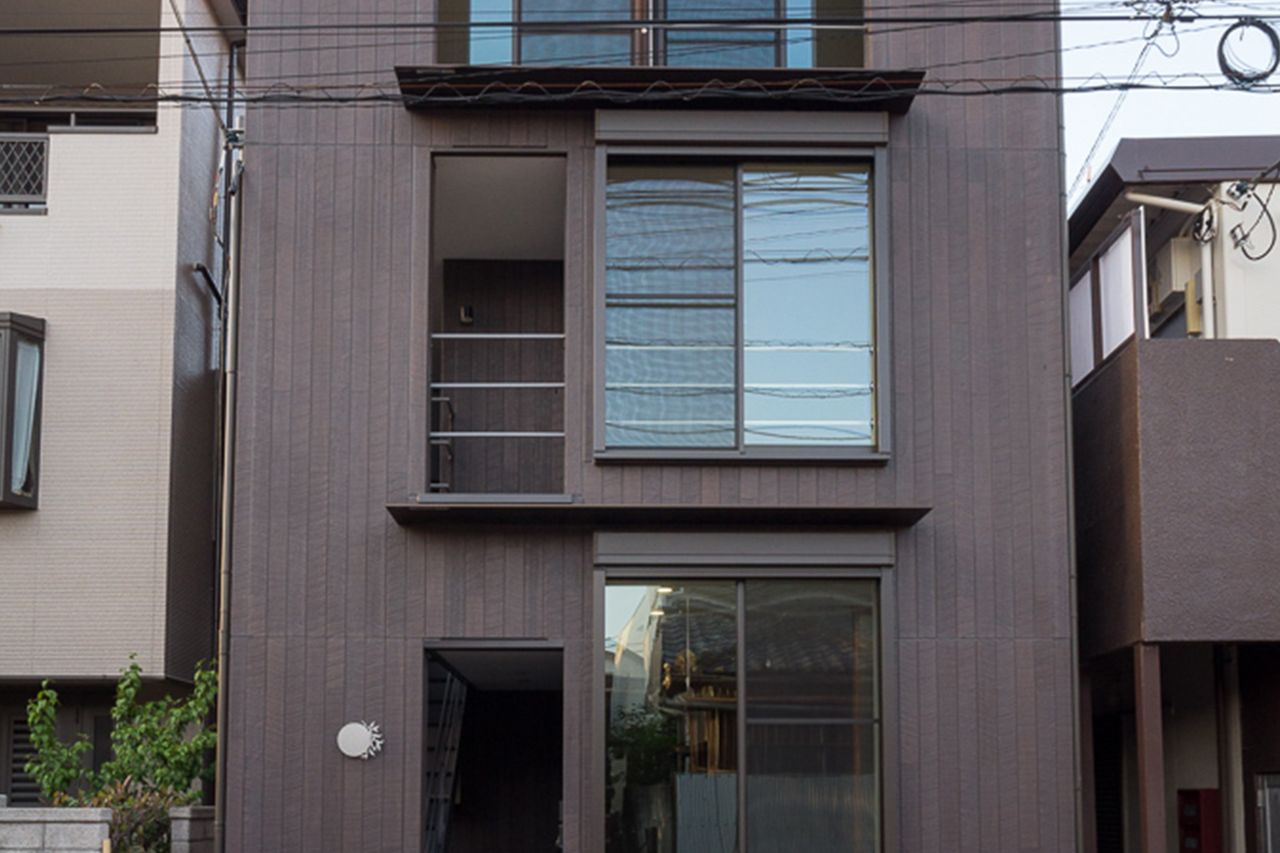 縦張りのこげ茶の外壁が、縦長の建物を端正に見せます