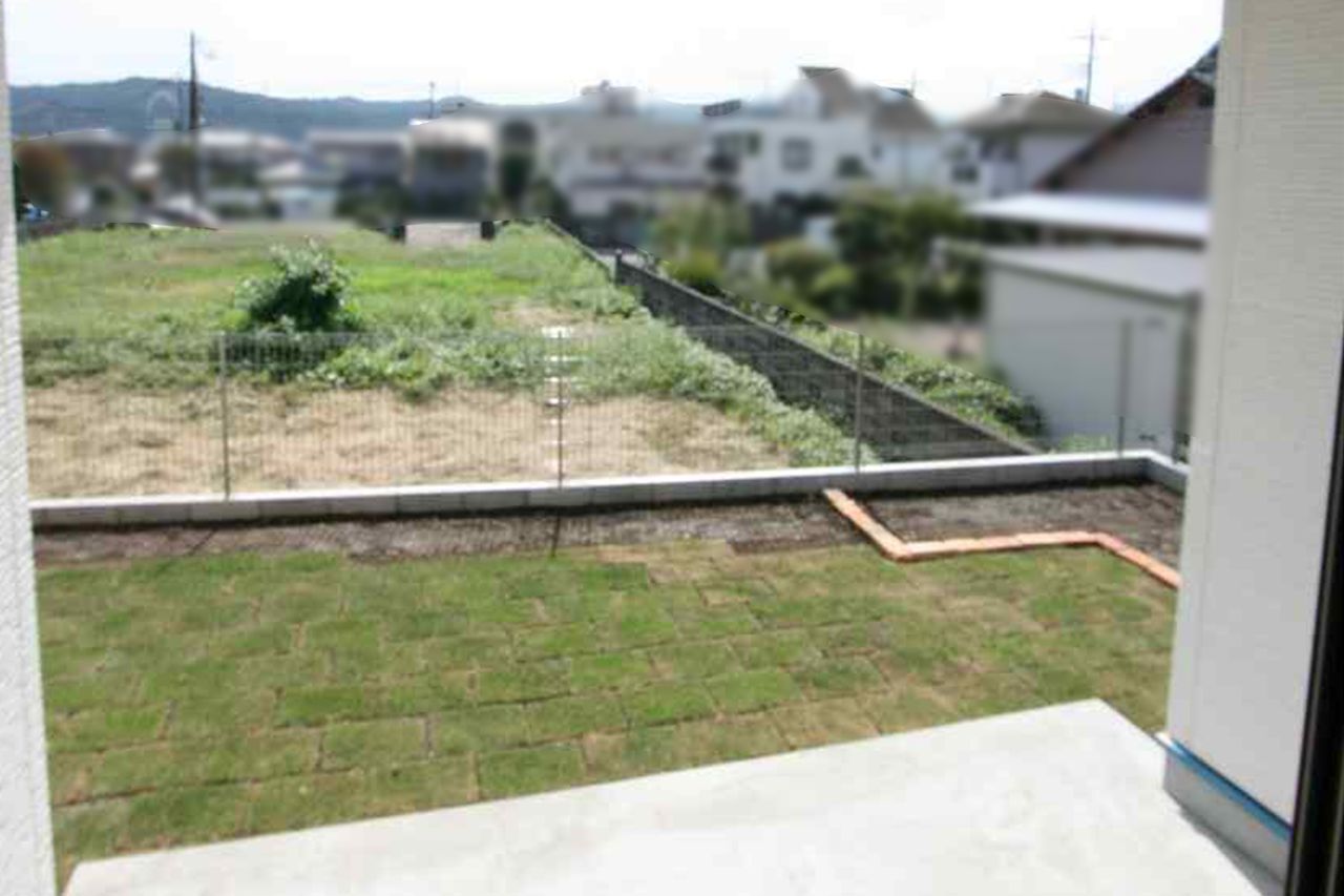 室内から芝の庭を見たところ、その先に景色が開けます