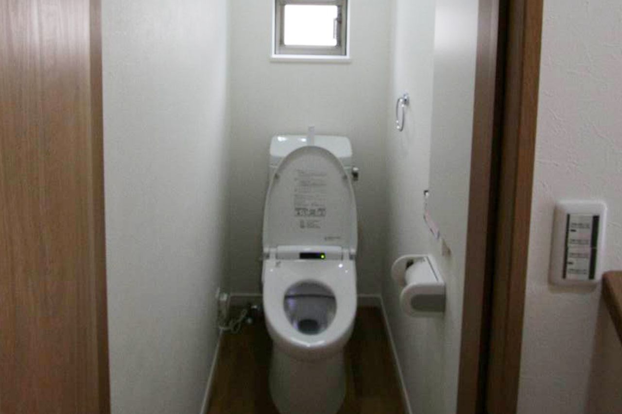 小窓で明るさと換気を確保した、白い壁のトイレ