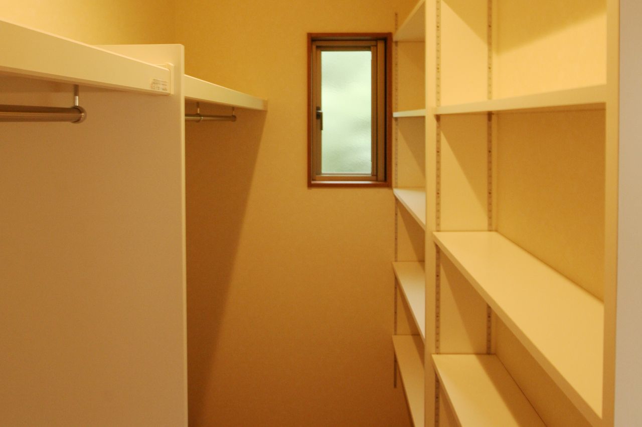 ハンガーパイプと棚で両側を使い切る、小窓付きの収納室
