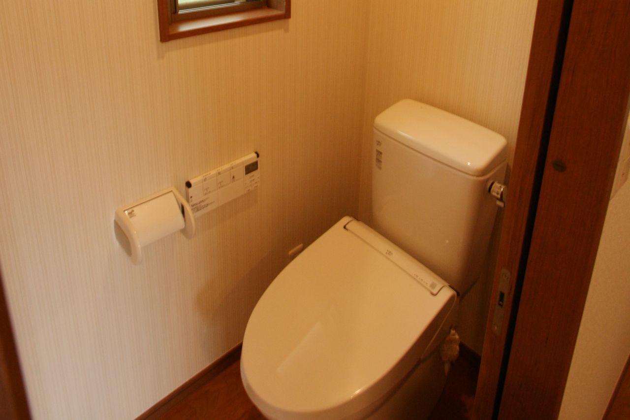 トイレは縦縞の壁紙、高い位置に木枠の小窓があります