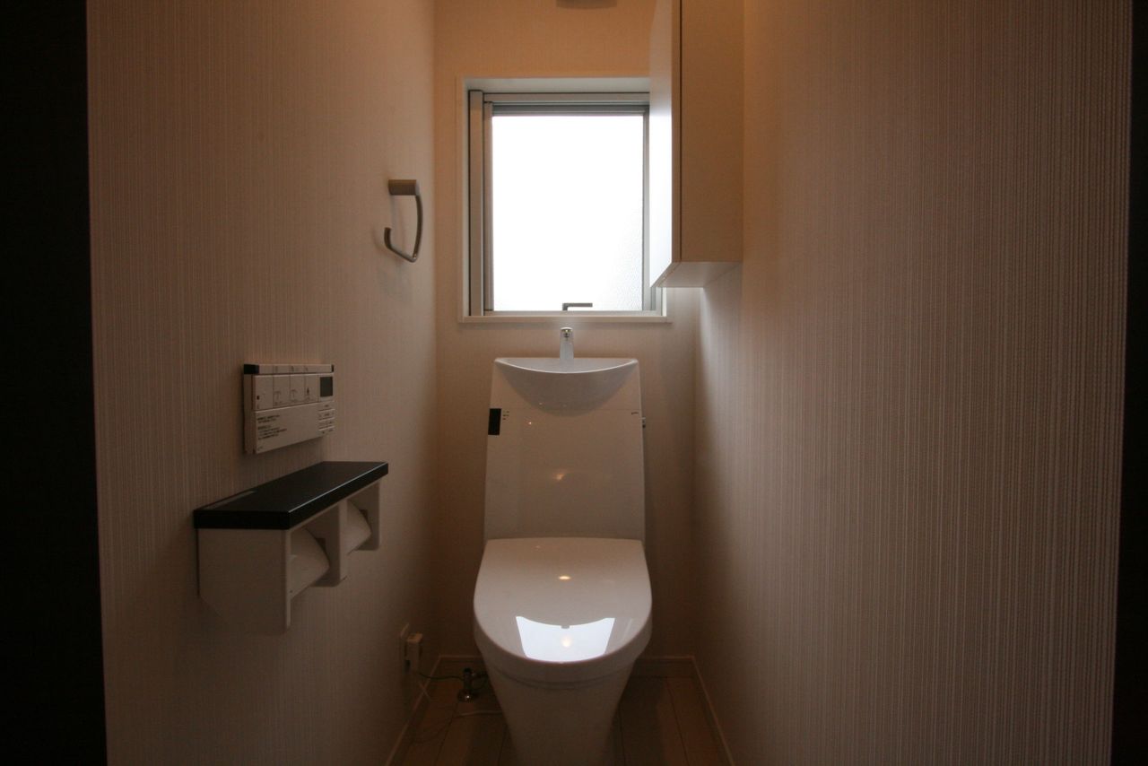 トイレは正面に窓、上部に吊り戸棚を設けて収納を確保